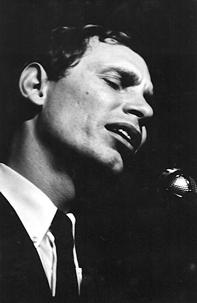 Black and white photo of Jean-Pierre Ferland singing, in a jacket and tie.