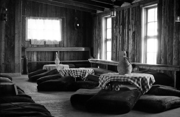 One of the two mezzanines at La Butte with low tables covered in checkered tablecloths, each with their candle stuck in a Chianti bottle and cushions on the floor.