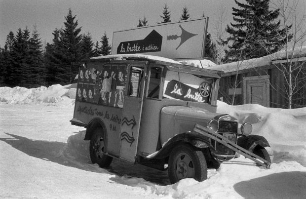 Black and white photo of an old delivery truck from the 1930s with signs on it indicating the way to La Butte.