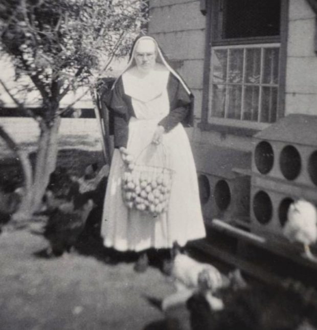 Black and white photo of a nun with a large metal basket filled with eggs.