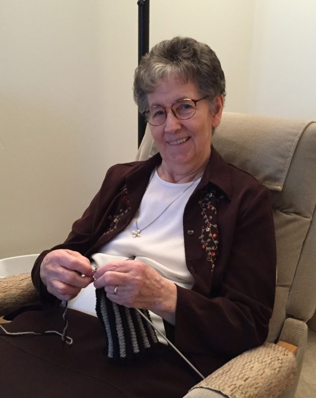 Elderly woman sitting in a rocking chair knitting.