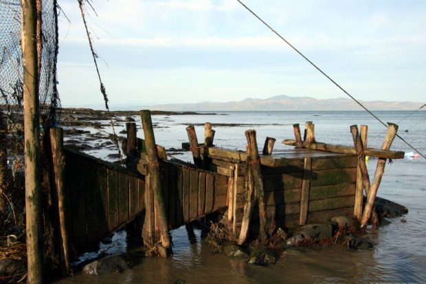 Two wooden funnels at the end of which is a large wooden box in which eels are held captive in a weir The first funnel, to the left, is called an ansillon and the second one, a bourrole.