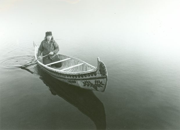Photo of César Newashish in his birch bark canoe.
