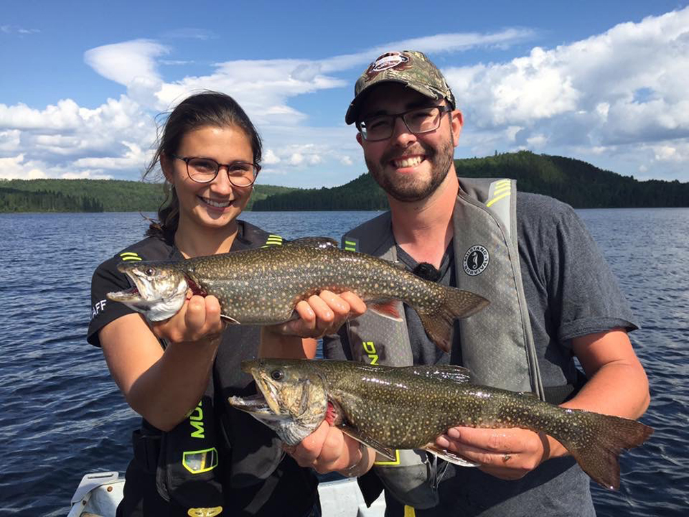 A guide and their customer, holding two speckled trout.