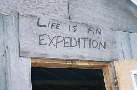 Writing on wood above door to unpainted shack.