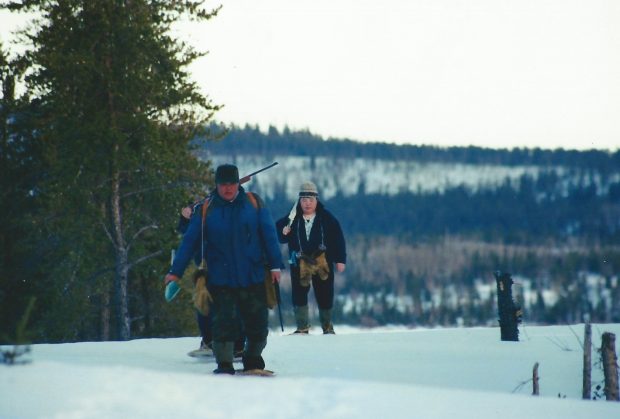 Three people walking snow covered hills in winter