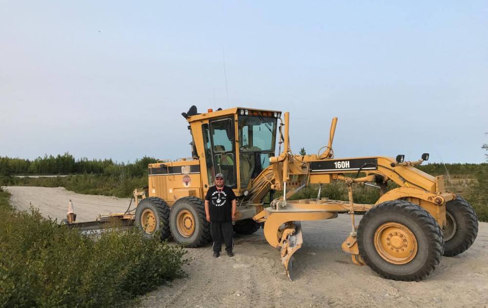 Man standing by yellow road grader.