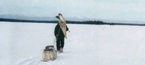 Homme tirant un traîneau sur un lac gelé.