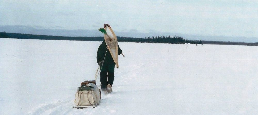 Man pulling sled across frozen lake
