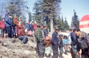 Men, women and children gather on the bank near float plane.