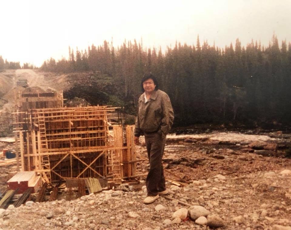 Man in brown jacket standing on rocky road.
