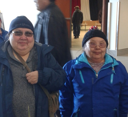 Two women wearing hats and glasses look at the camera