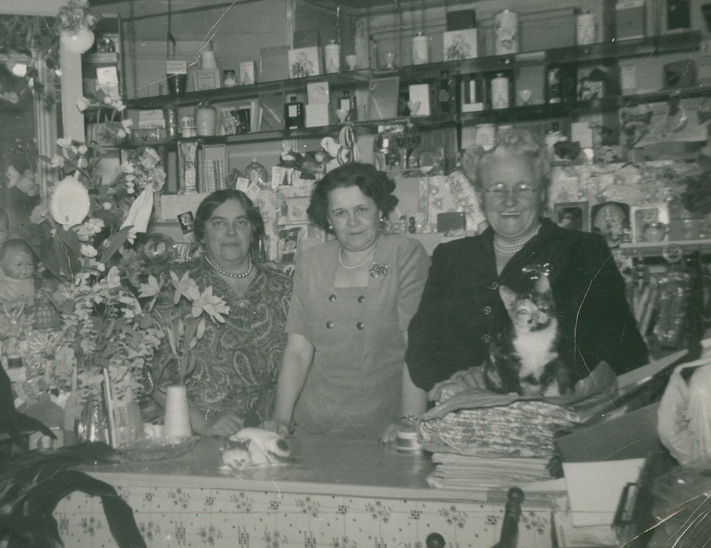 Black and white photograph of three women behind a store counter.