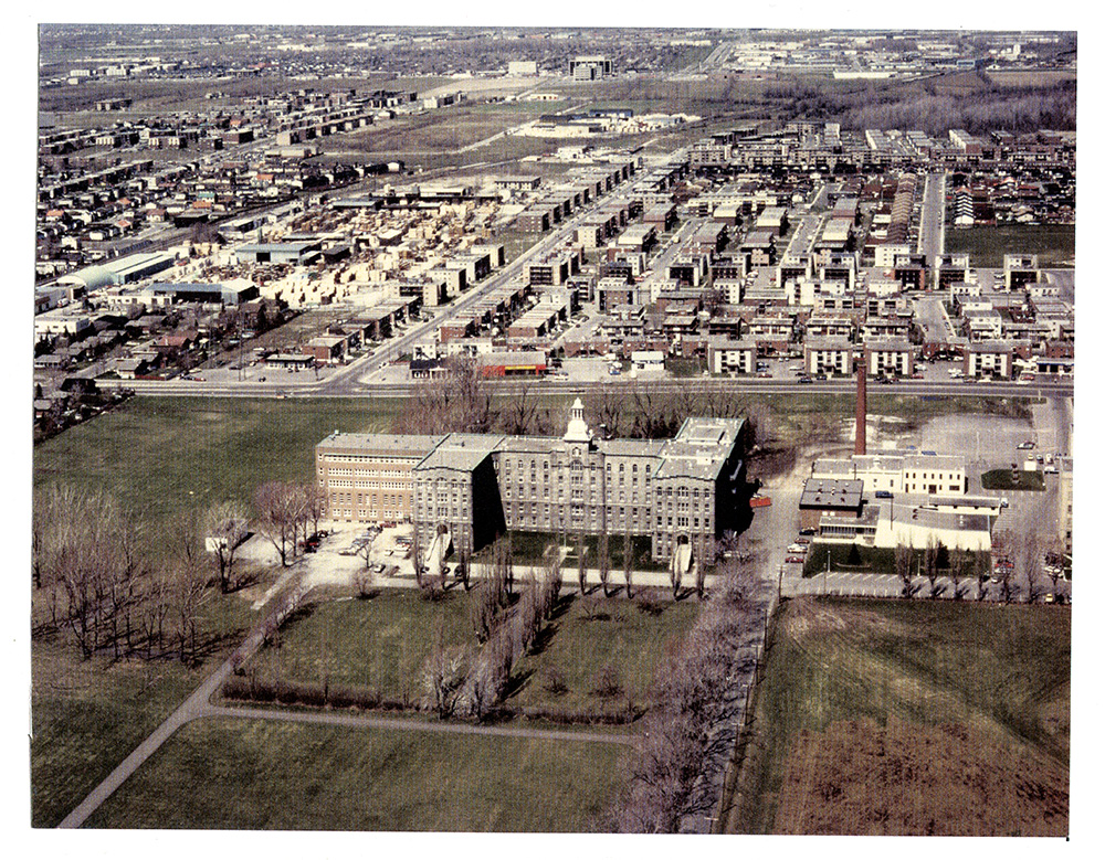 Vieille photographie aérienne en couleur offrant une vue sur les rues résidentielles de St-Vincent-de-Paul, avec en premier plan, le collège Laval. 