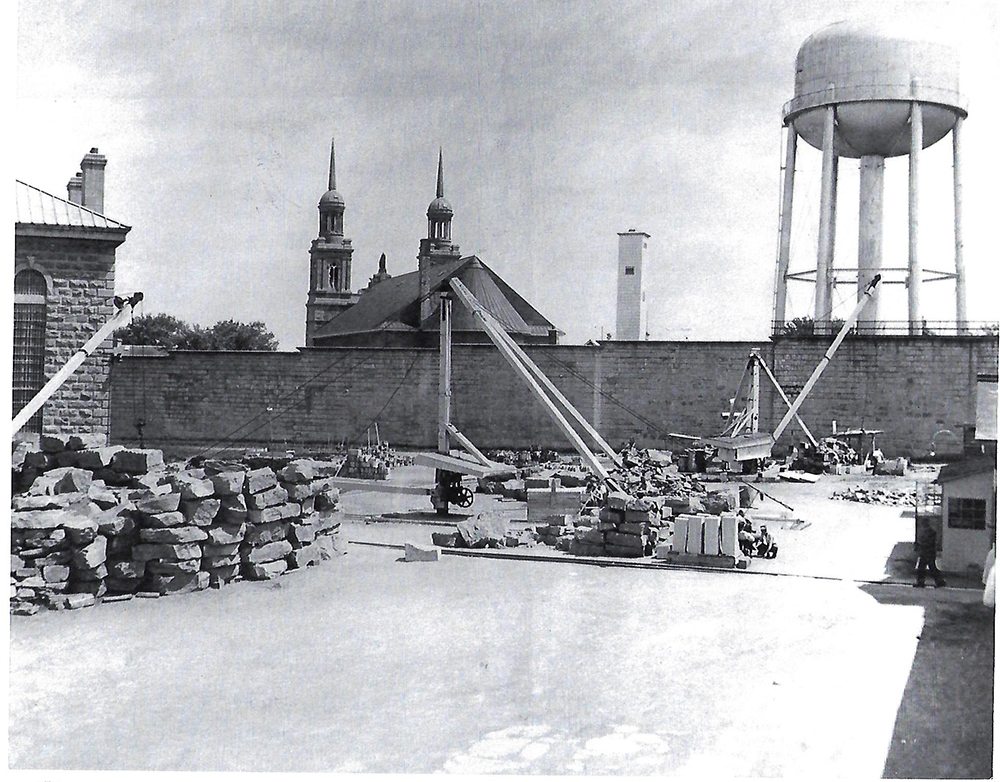 Black and white photograph of the Saint-Vincent-de-Paul penitentiary, inside the walls. In the photograph, men can be seen cutting stone.