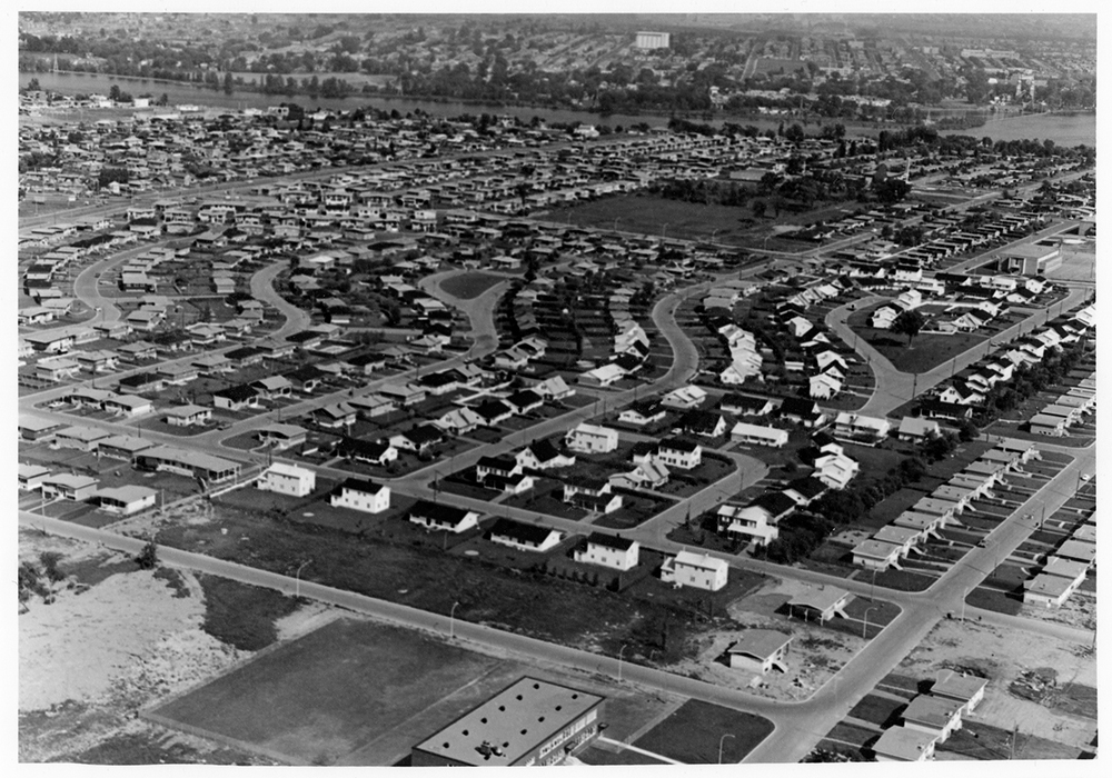Photographie en noir et blanc présentant une vue aérienne d’un quartier résidentiel près d’une carrière. 