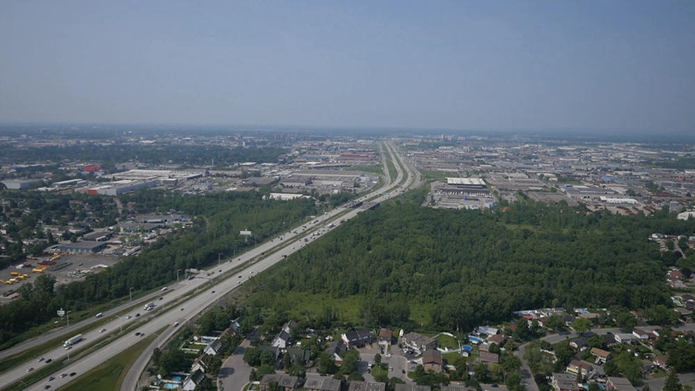 Photographie aérienne en couleur. Vue sur l’autoroute Jean-Noël Lavoie et le secteur industriel de Laval.