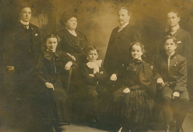 Family picture in sepia color. In the background are Théophile, Célina-Elmire, Joseph-Adélard senior and Joseph-Albert. In front, the 4 children are sitting. They are Aimée, Auguste, Marie-Rose and Joseph-Adélard Junior.