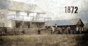 Group in front of wooden buildings and fence