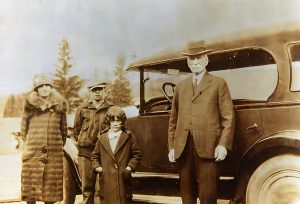 Man, woman and 2 children in front of vintage car
