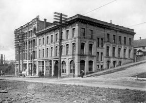 Two buildings and wagon on hillside city street