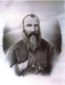 Head and shoulders photo of priest with hand in cassock