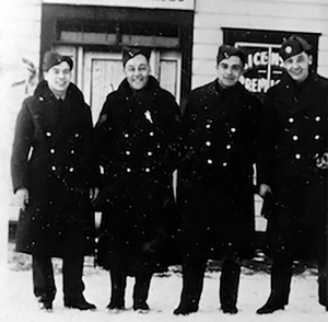 Four men in military uniform standing before building