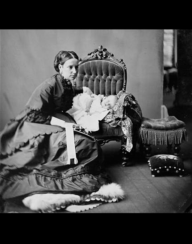 Lady Agnes Macdonald crouches next to a chair in which her baby Mary is propped, 1868.