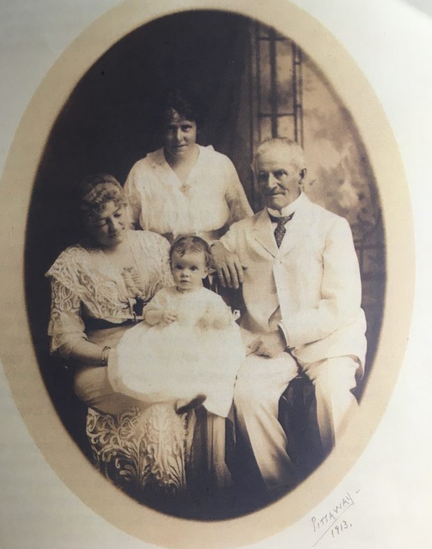 Oval sepia-toned photograph of four people (the Bate family) including an elderly man (Sir Henry Bate), a baby (his granddaughter), and two women (his wife and daughter) all dressed in white.