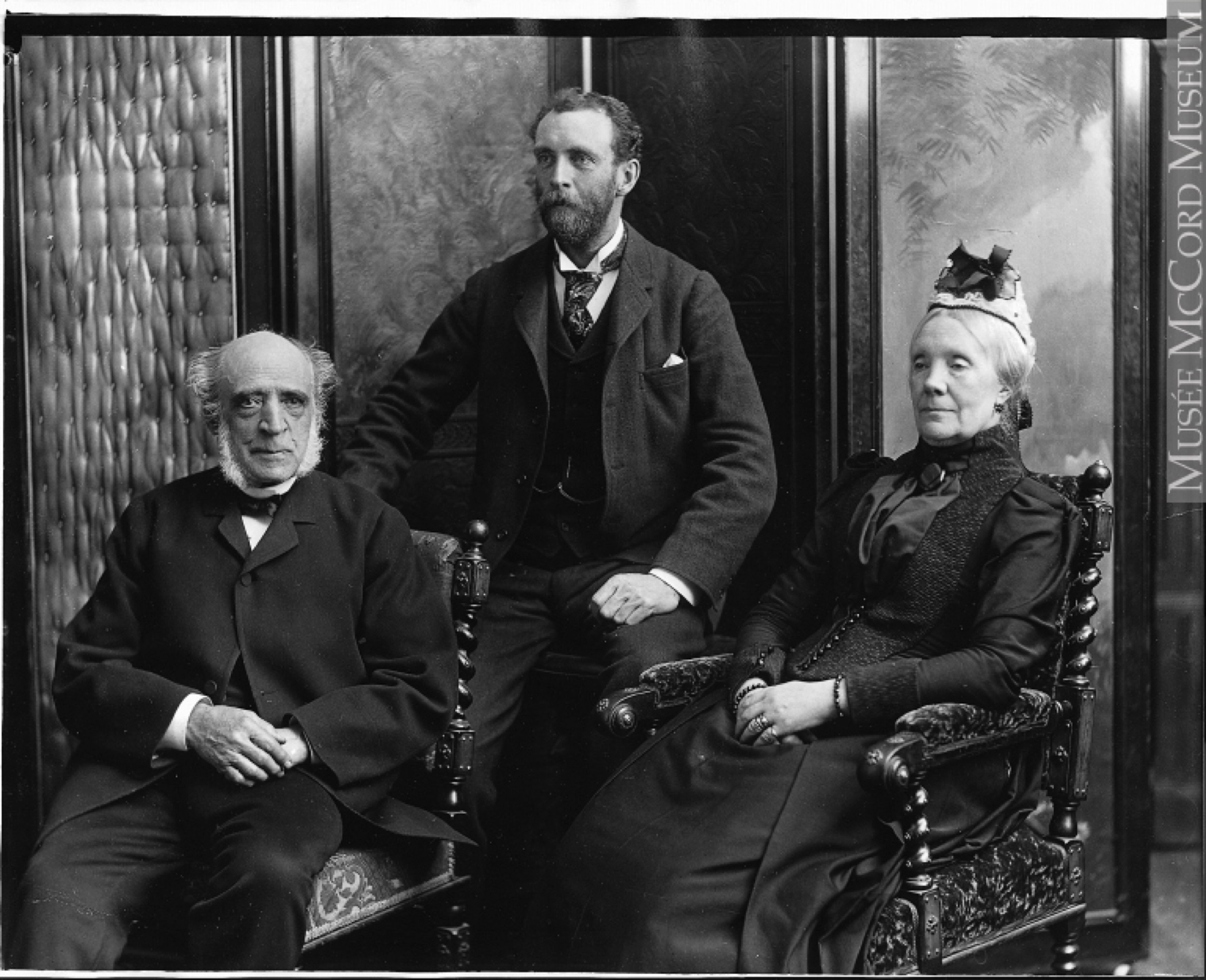 Formal black and white photo of three seated people (William C. Meredith, his wife Sofia Naters Holmes Meredith, and their son Henry Meredith), on elaborately carved chairs, the elderly couple in front, and the younger, bearded man seated behind them on a stool.