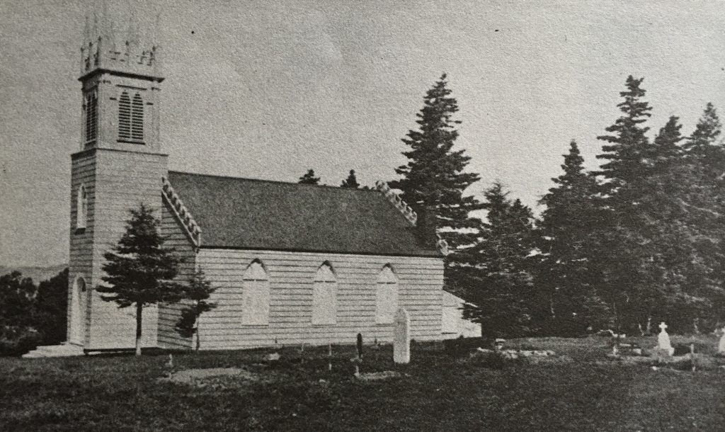 A black and white image of a wooden St. Bartholomew's anglican church with a square steeple at the front, and a graveyard in the foreground.