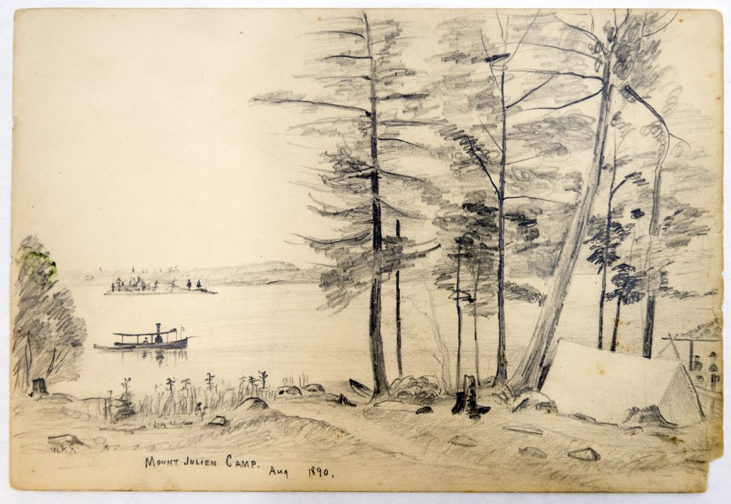 Lake scene looking out from shoreline, showing a small boat in the water and a campsite beneath trees in the foreground.
