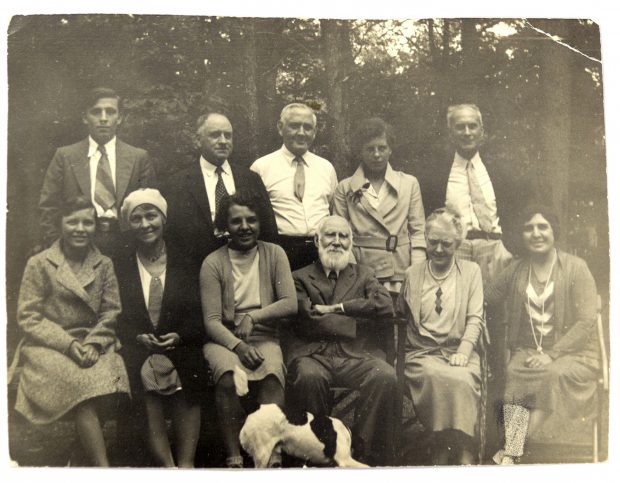 Image of black-and-white photograph showing eleven people and dog