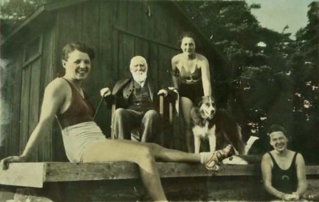 Image of people posed informally on a dock, with a large structure in the background