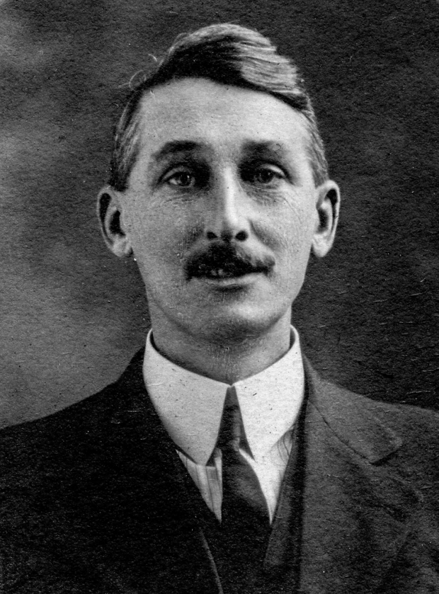 Black and white archival photograph of a man with a moustache wearing a suit, and tie.