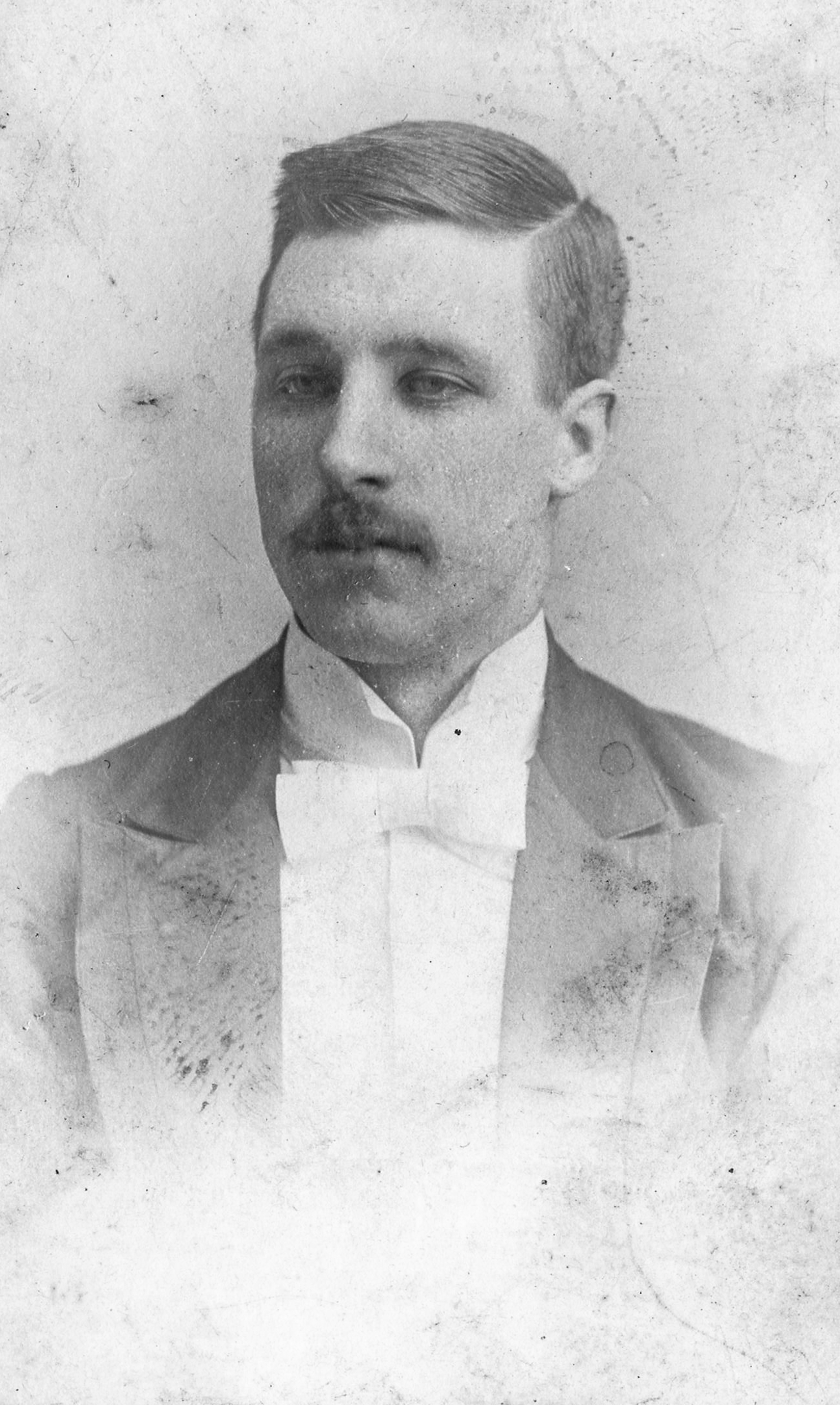 Black and white archival photograph of a man wearing suit, and bowtie.