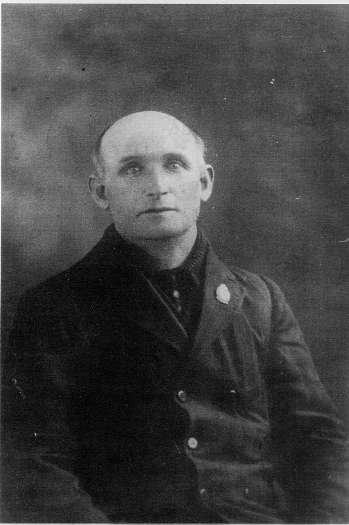 Black and white photograph of a balding man wearing an overcoat.
