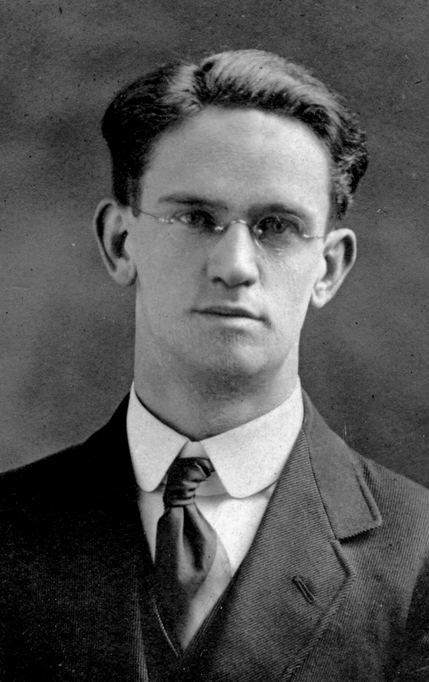 Black and white archival photograph of a man with eyeglasses wearing a suit, and tie.