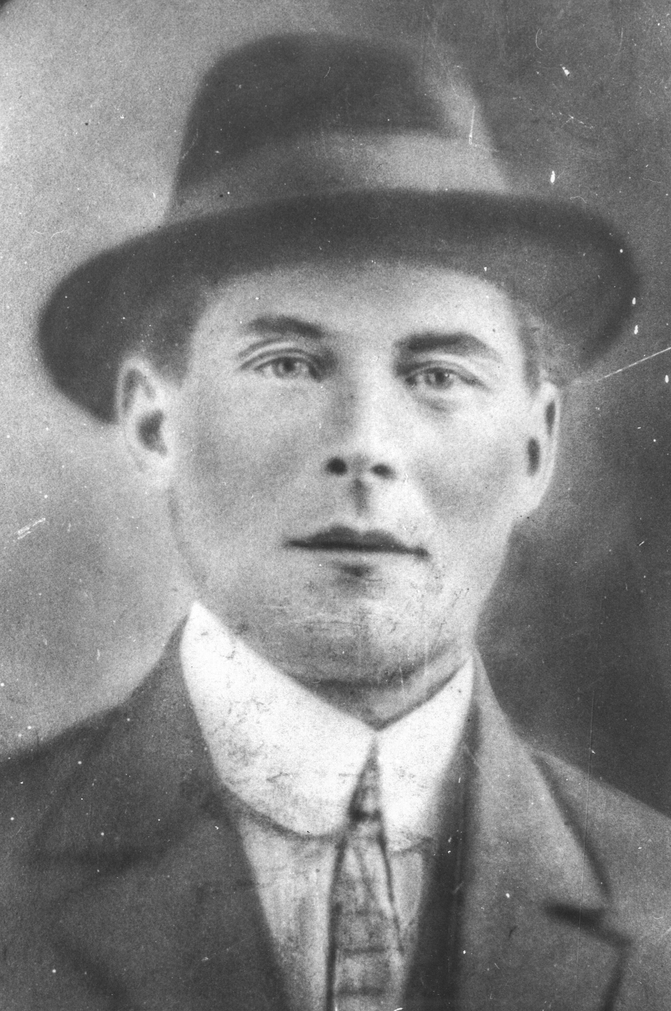 Black and white archival photograph of a man wearing a fedora hat, suit, and tie.