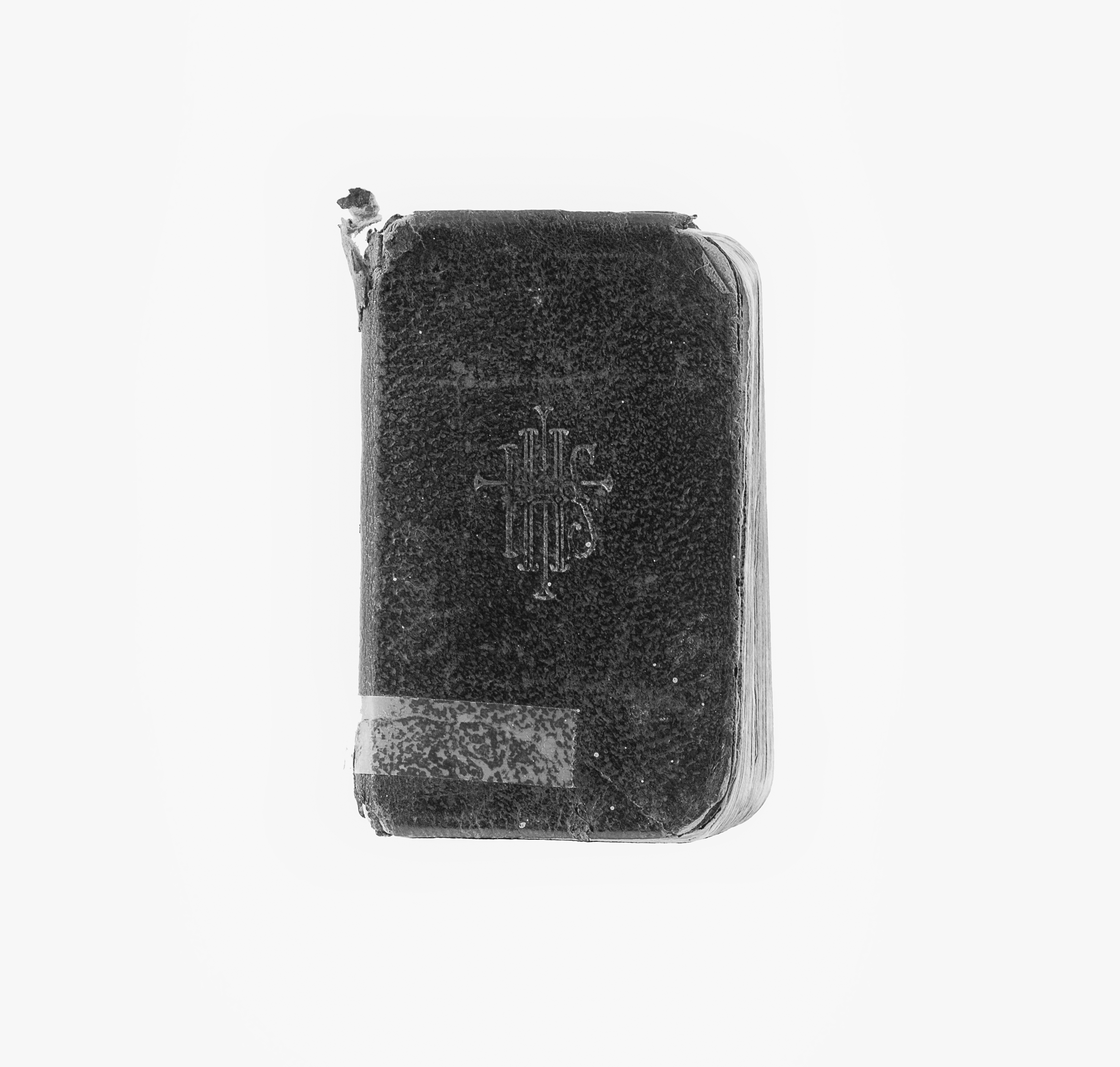 Black and white modern photograph of prayer book with black cover and white pages. Cover has IHS inscribed on the front.