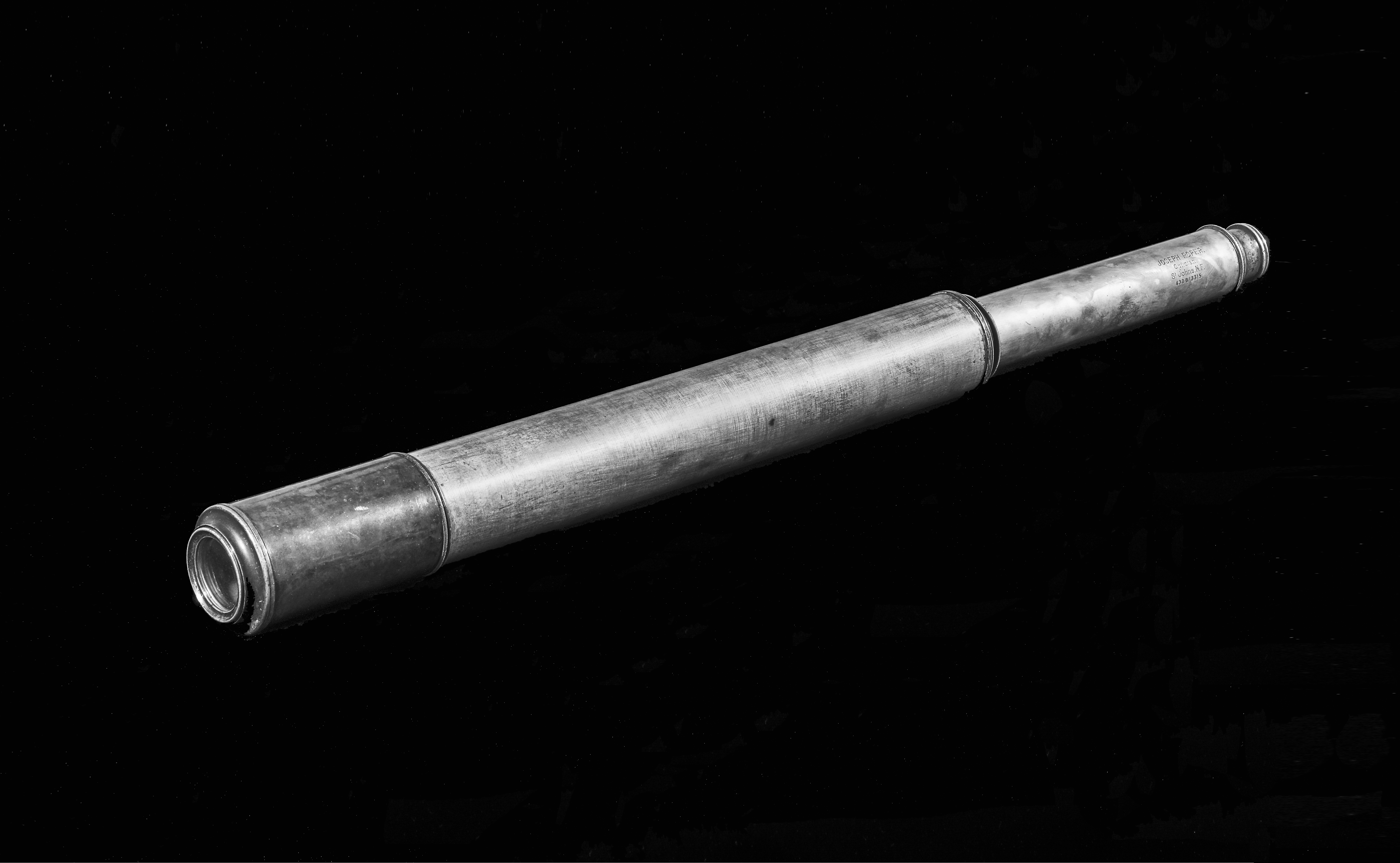 Black and white modern photograph of a metal telescope.