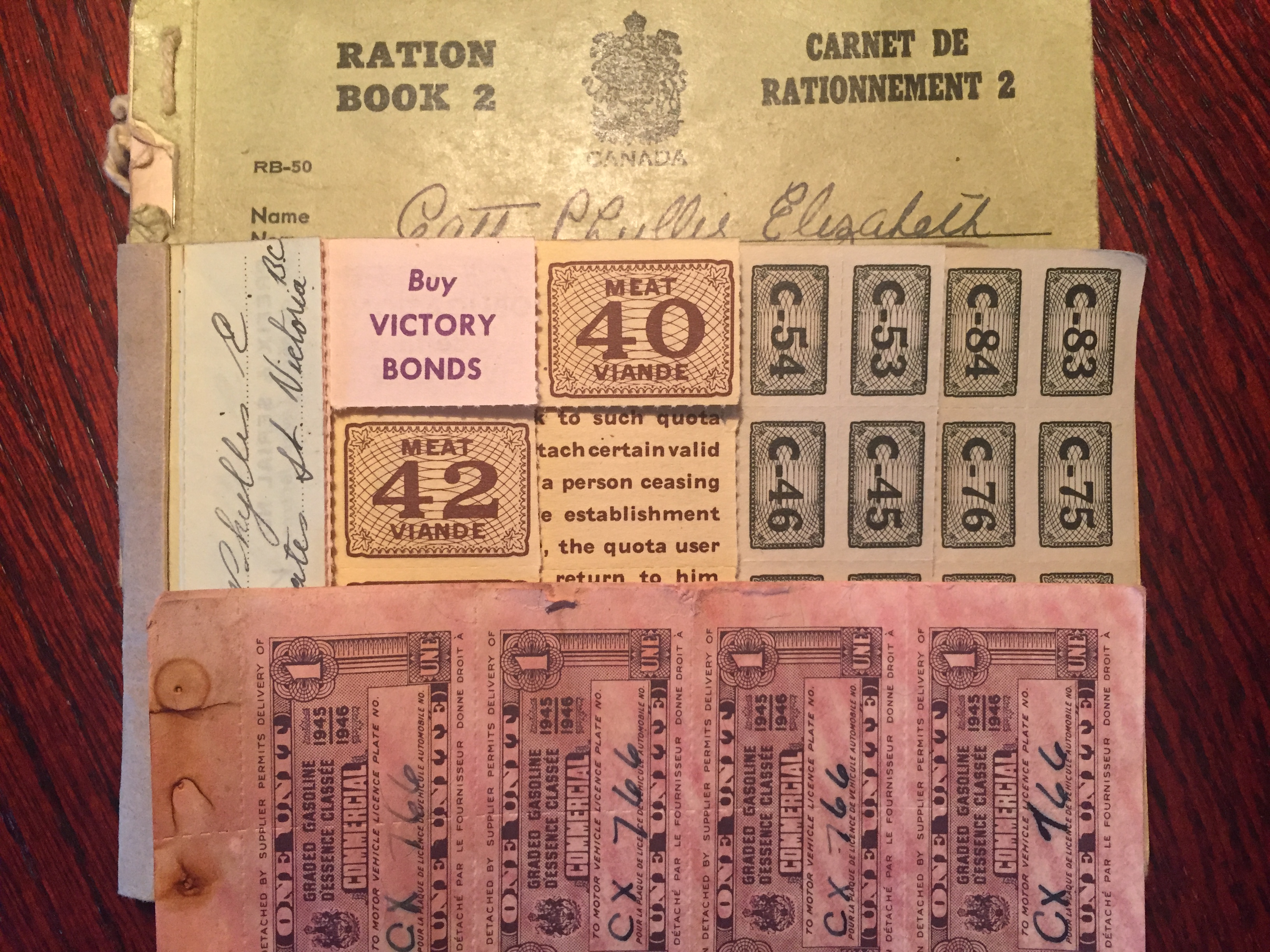 A ration book from World War 2 with the name “Catt, Phyllis Elizabeth” contains ration stamps. One of the stamps reads “Buy Victory Bonds”.