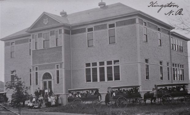 Teachers and students pose on school steps and in three school vans.