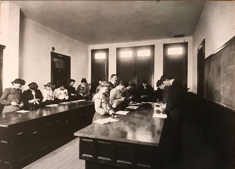 Un enseignant surveille ses élèves dans le laboratoire de chimie. Dix jeunes femmes et trois jeunes hommes travaillent avec assiduité. 