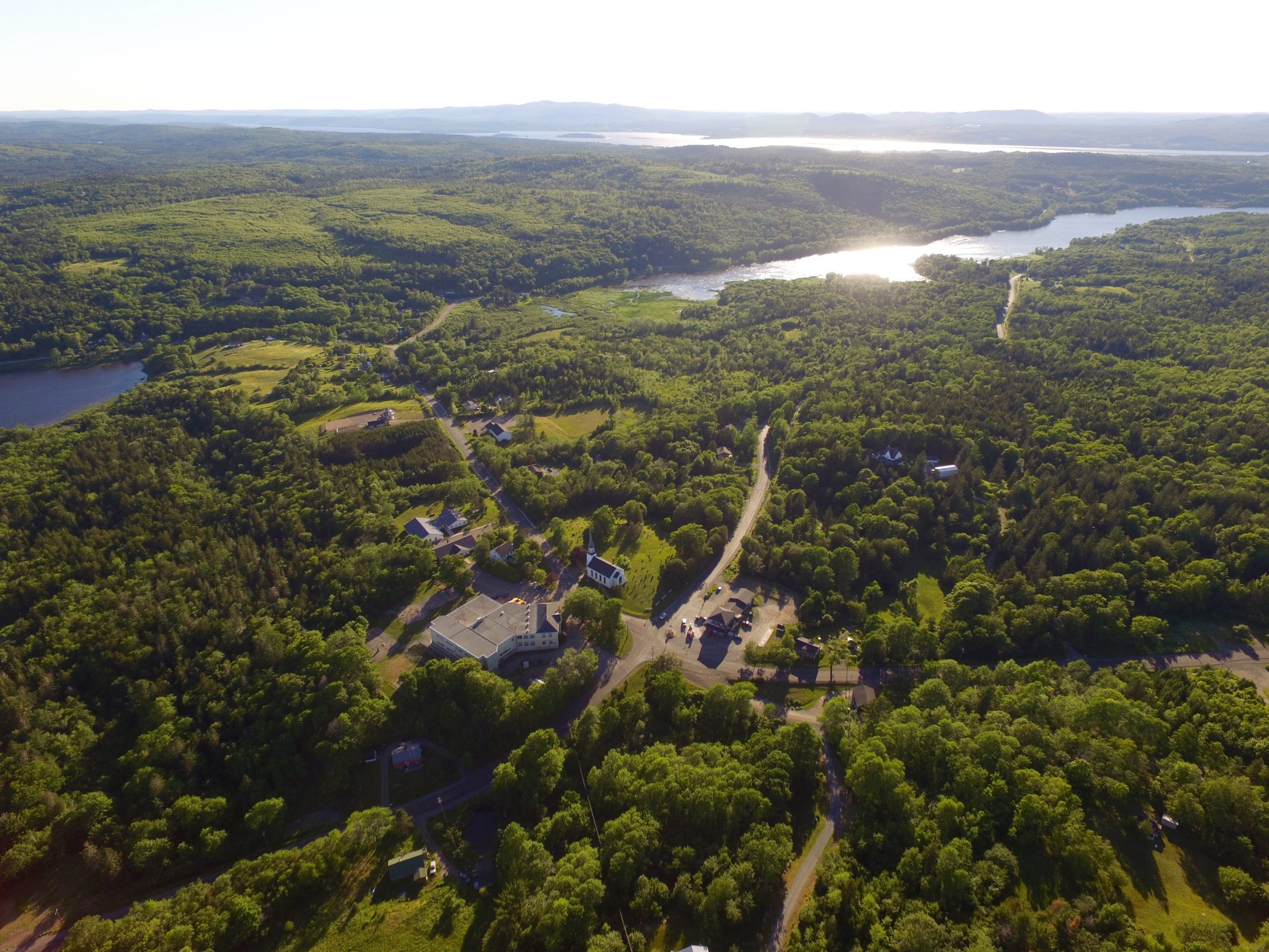 Aerial view of treed rolling hills and 3 bodies of water.