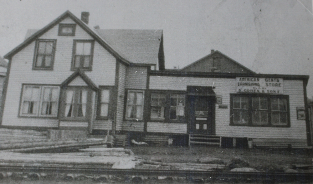 Black and white archival photograph. Street view. Exterior view of American Gents Furnishing Store S. Cohen & Sons on Main Street. Sign above right window reads: AMERICAN GENTS FURNISHING STORE [unintelligible] S. COHEN & SONS.