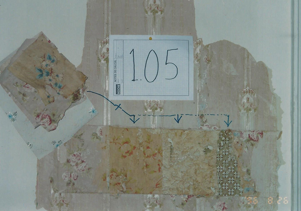 Colour close-up photograph of part of a wall, showing the different wallpaper that covered it over the years.
