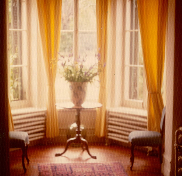 Colour photograph of the entrance hall of Manoir Fraser with a bouquet of flowers in the bay window.