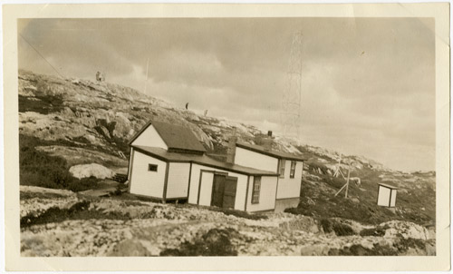 Two small buildings and an antenna on a barren rocky slope.