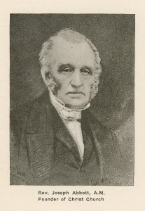 Black and white portrait of an elderly Reverend Joseph Abbott, head and shoulders. He has short hair and grey and white sideburns, and is looking at the camera with a serious expression. He is wearing a black minister’s robe and a white collar. The background is black. The inscription under the portrait reads “Rev. Joseph Abbott, A.M. Founder of Christ Church”.